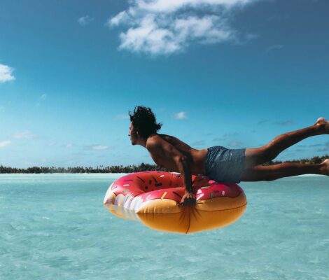 A man swimming in the ocean with inflatable donut ring.